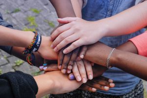 Hands of teens coming together to show solidarity and support, promoting the Hope Empowerment Coalition efforts.