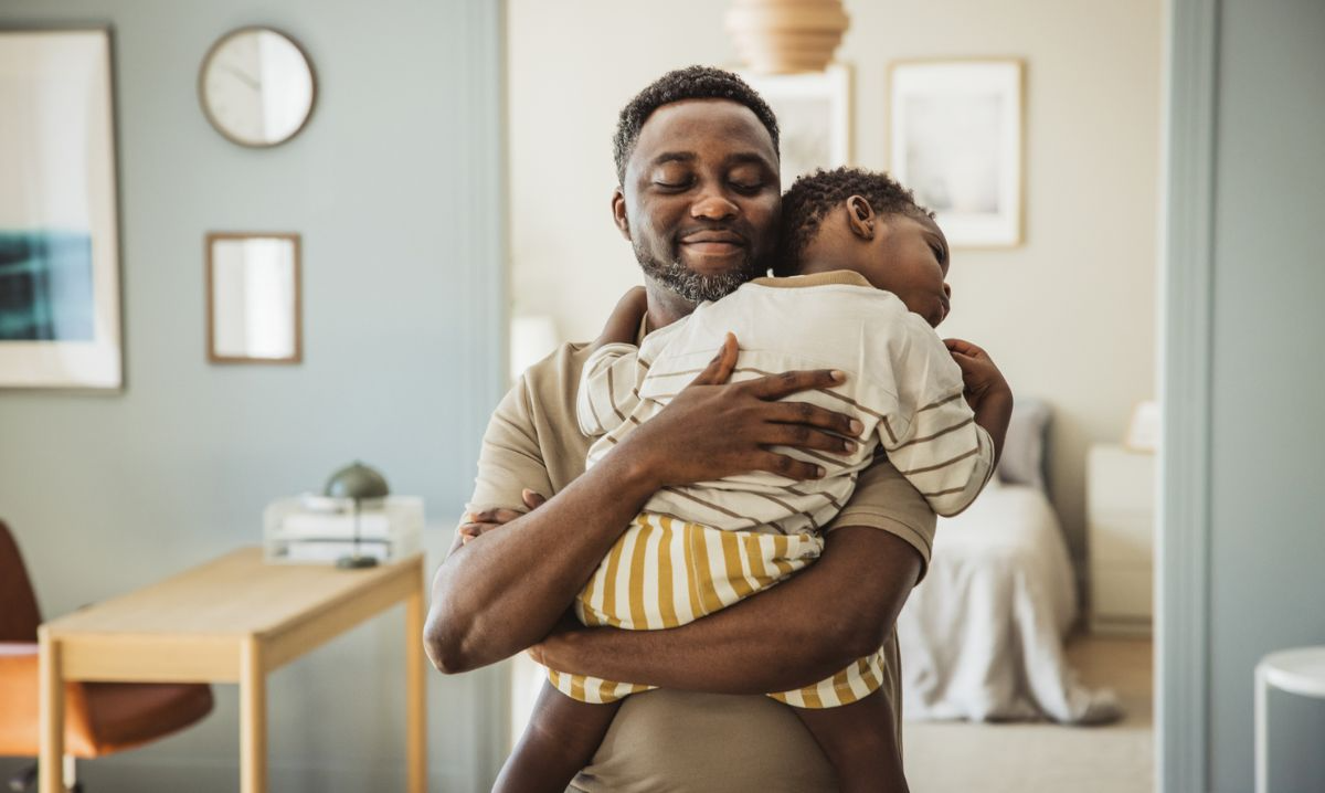Father holding young child in a comforting embrace, illustrating early relational health and the importance of caregiver-child bonding in early childhood mental health care.